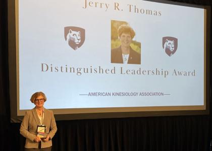 Nancy Williams holding award in front of screen reading Jerry R. Thomas Distinguished Leadership Award