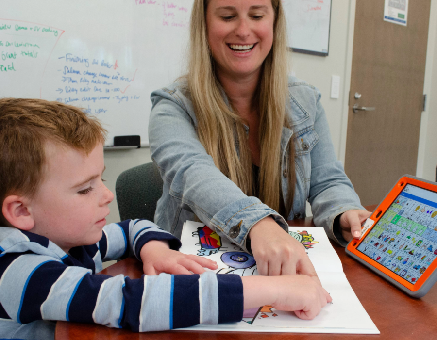 Graduate student works with a child using an AAC device