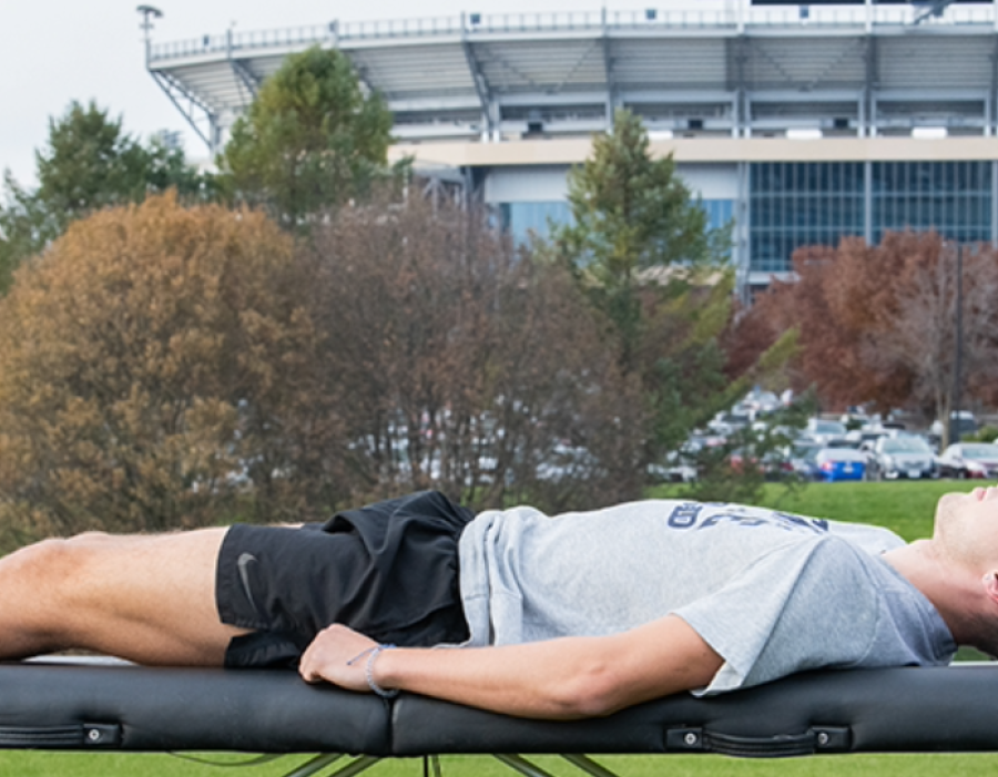 An athletic training student works with an athlete on the lawn at Beaver Stadium.