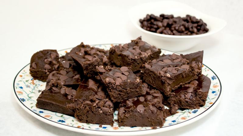 Black bean brownies on a plate and a small bowl of black beans in the background.