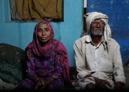 Older person with scarf on head and older person with head covering sit in their modest home