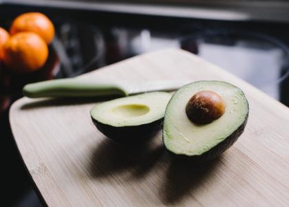 An avocado cut in half and lying on a cutting board