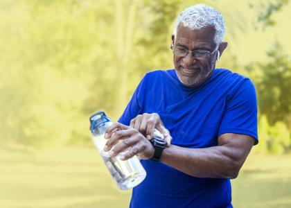 Older man holding a water bottle and checking his smartwatch