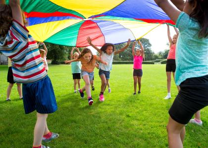 children playing in a field under a colorful parachute