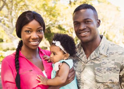 smiling father and mother holding baby, father is wearing military uniform