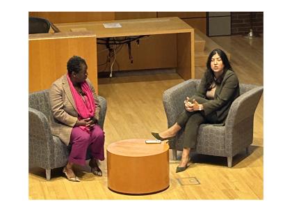 Two women speaking at an event, sitting across from each other in chairs