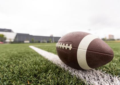 a football in the foreground rests on a football field