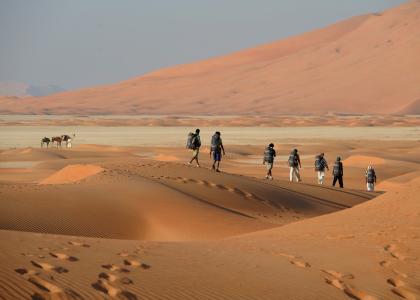 Outward Bound students walk across a desert wearing backpacks
