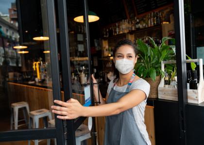 Woman in mask opening a restaurant for business