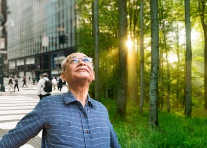 Older man looks at the sky over a background that is half urban, half forest. 