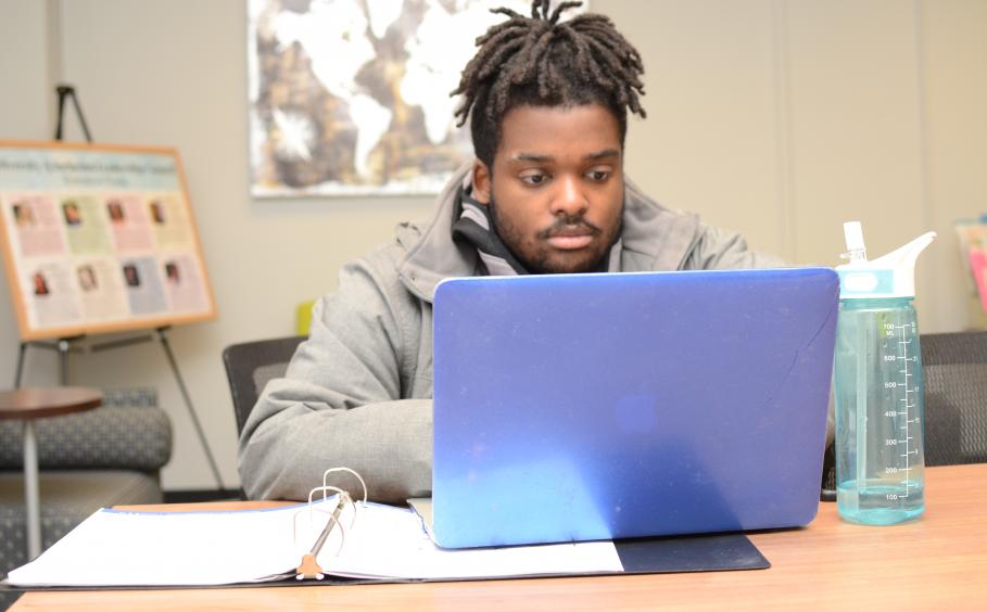 Student working in the office for diversity and inclusion on his laptop