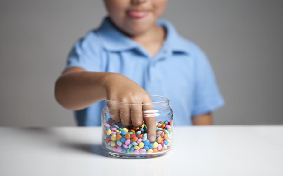 child reaches into a jar of candy