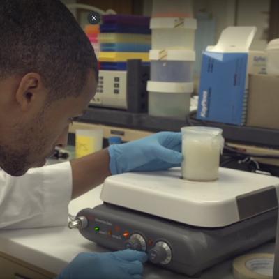 Graduate student focuses on liquid in a beaker on lab equipment