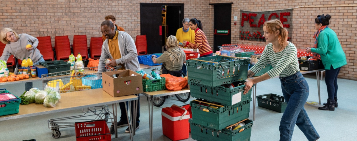 Several adults work together to move and organize food donations in a food donation center.