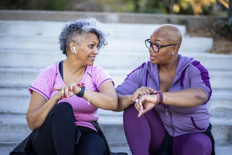 Two women discussing their smart watches after exercise