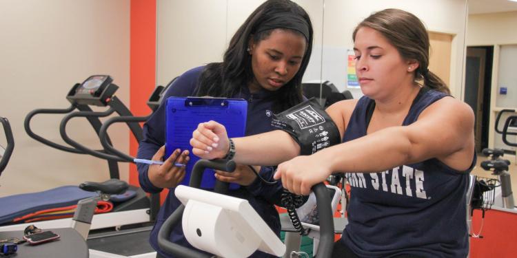 Student researcher checks vitals of a volunteer on an exercise bike
