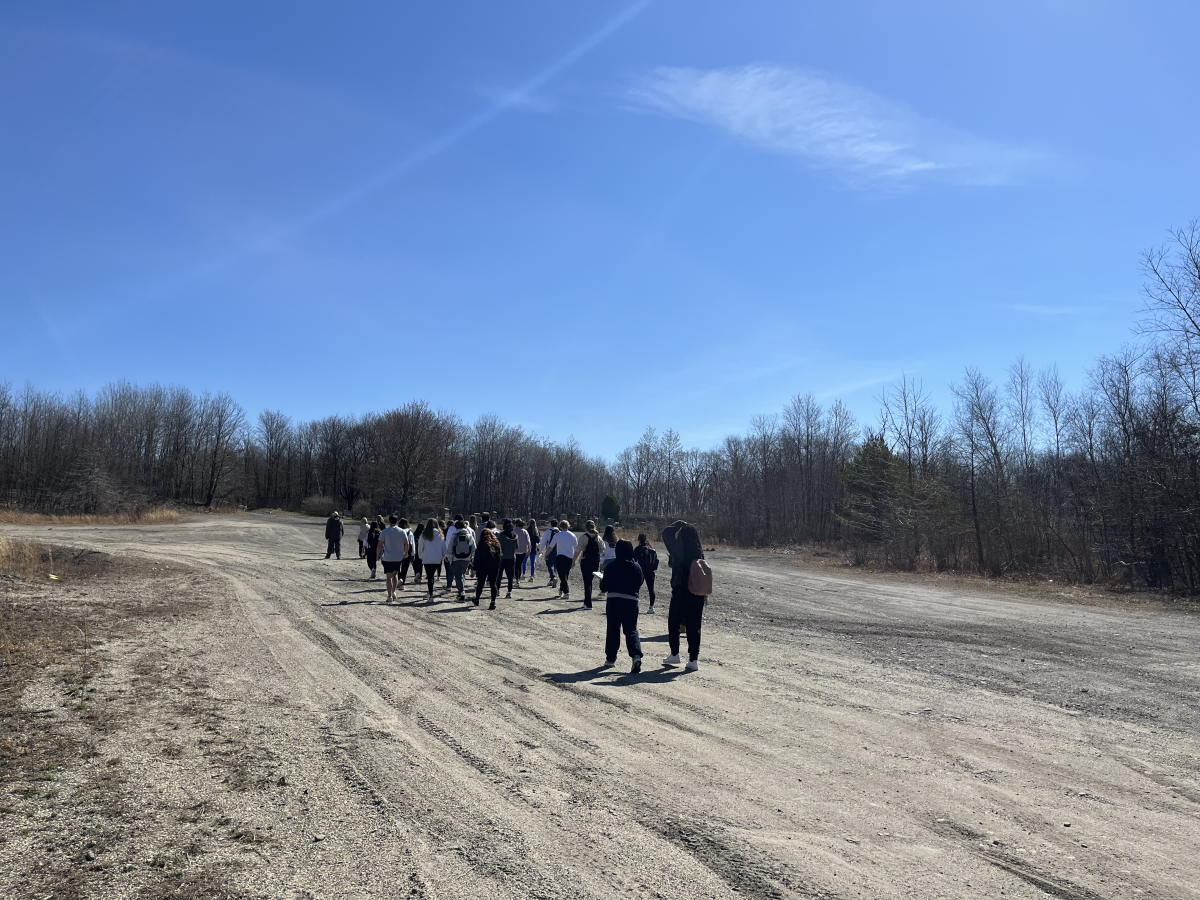 =A group of people walking on a dirt road with a barren landscape in the background.